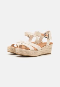 Sandali wedge espadrille beige con fasce in tessuto intrecciato e fibbia alla caviglia. La piattaforma presenta un design in juta texturizzato e una soletta in suede liscia.