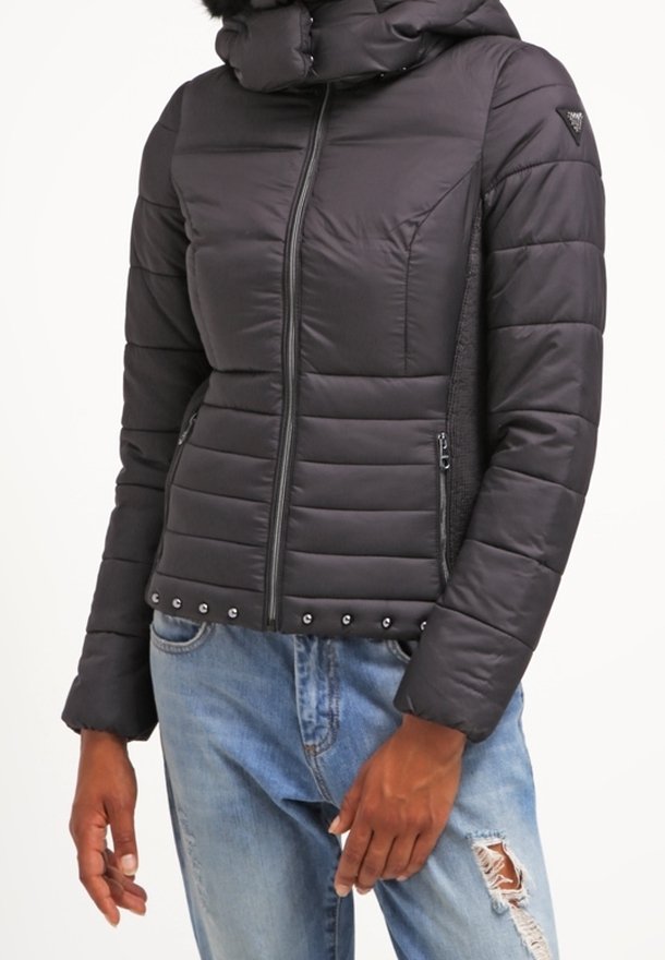 Svart vadderad jacka med hög krage, horisontella sömmar, blixtlåsförsedda fickor och dekorativa nitar längs fållen.