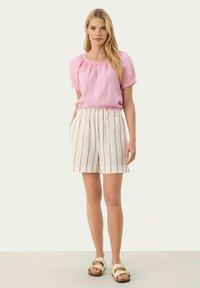 Light pink, short-sleeve blouse with a round neckline and gathered detail, paired with beige striped shorts featuring an elastic waistband.