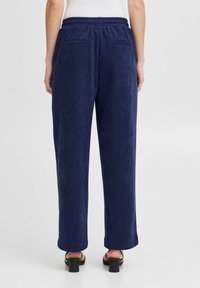 Pantalons en velours côtelé bleu marine avec une taille élastique, jambes droites et deux poches arrière. Texture lisse et design taillé.
