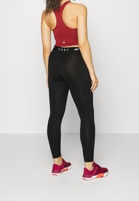 Svarta leggings med hög midja, kombinerade med en röd sportig cropped topp och röda sneakers. Slät textur och åtsittande design.