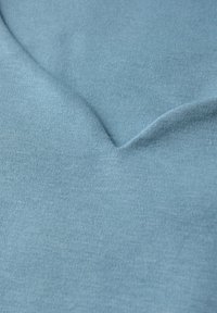 Blå stickad tyg med en slät textur och subtil ribbning. Det har ett mjukt vågmönster som betonar mjukhet och flexibilitet.