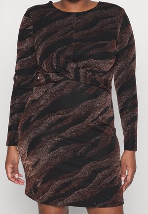 Femme portant une robe à manches longues, longueur genoux, avec un motif de rayures de tigre noir et brun métallique et un design torsadé sur le devant.