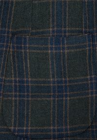 Tkanina wełniana w kratkę, z ciemnozielonymi, granatowymi i brązowymi liniami, z kieszenią w zaokrąglonym kształcie.