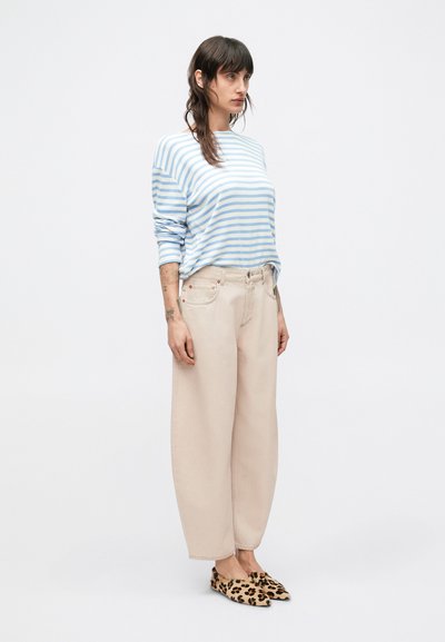 Μπλούζα με μπλε και λευκές ρίγες και μακριά μανίκια, κρεμ παντελόνι με φαρδιά πόδια και παπούτσια slip-on με λεοπάρ μοτίβο. Ύφασμα απαλό με χαλαρή εφαρμογή.