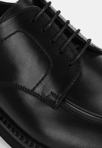 Schwarze Leder-Dressschuhe mit glatter Oberfläche, runder Zehenform und traditionellem Schnürdesign mit sechs Ösen. Dezente Nähte sind sichtbar.