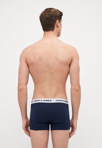 Dunkelblaue Boxershorts mit einem weißen Bund, auf dem "JACK & JONES" steht; der Stoff wirkt glatt und enganliegend und zeigt ein Modell mit mittlerer Bundhöhe.