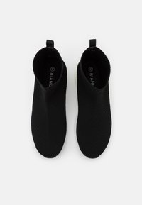Schwarze Slippers mit einem strukturierten Strick-Obermaterial und einer weißen Sohle. Verfügt über ein sockenähnliches Design mit einer Zuglasche an der Ferse. Größe 37.