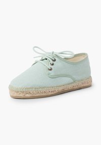 Espadrillas in tela azzurra chiara con design alla allacciazione, punta tonda, suola in corda di juta e dettagli di cucitura lungo il bordo.