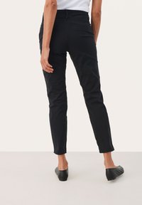 Black slim-fit pants with a smooth texture, mid-rise waist, and tapered legs. Featuring back pockets and a clean, minimalist design.