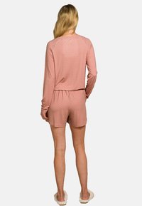 Roze pyjama set met een lange mouw top met een patroon en korte broek. Zacht materiaal met een elastische tailleband en een relaxte pasvorm.