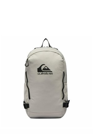 Hellgrauer Quiksilver-Rucksack mit schwarzem Logo, vorderen Reißverschlusstaschen, Seitenriemen und oberem Griff, auf weißem Hintergrund aufrecht stehend dargestellt.