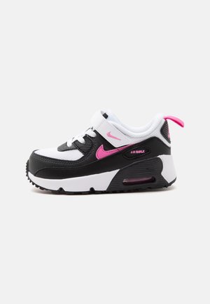 Basket Nike Air Max blanche et noire avec des accents roses, une bride Velcro et un coussin d’air visible dans la semelle épaisse.