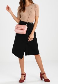béžový žebrovaný pletený top, černá asymetrická sukně, růžová kožená kabelka se zlatými doplňky a vínové vysoké podpatky.