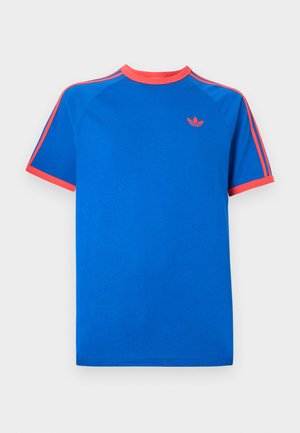 Blue cotton T-shirt featuring a solid blue body, raglan sleeves, coral neckline, and coral stripes with a small logo on the chest.