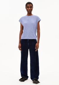 Striped blue and white cotton short-sleeve top paired with navy blue wide-leg corduroy pants and black fringed shoes.