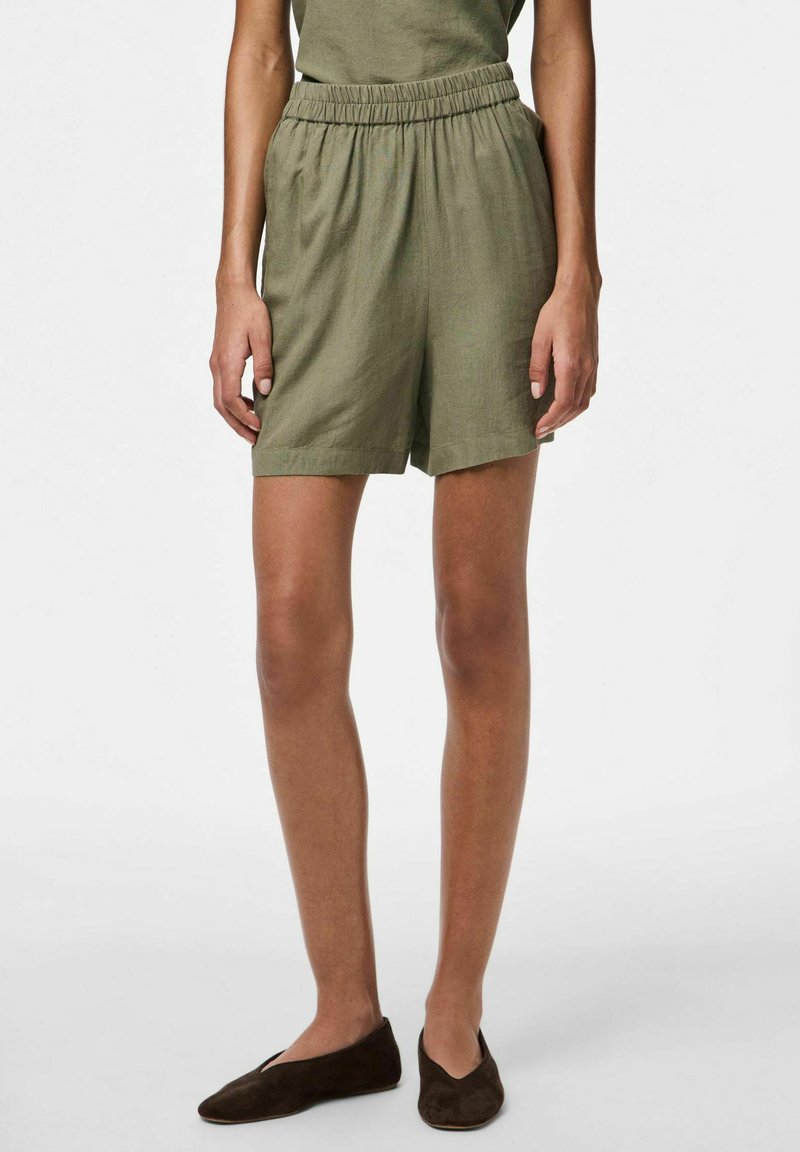 Pantaloni corti in lino verde oliva con vita elastica, vestibilità rilassata e tasche laterali. Tessuto morbido e design di lunghezza a metà coscia.