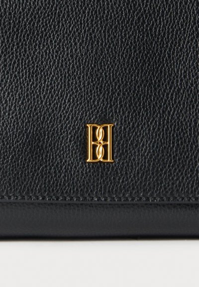 Μαύρο πορτοφόλι από υφή δέρματος με χρυσή μεταλλική λεπτομέρεια με στυλιζαρισμένο λογότυπο, που παρουσιάζει μοντέρνο και κομψό σχεδιασμό.