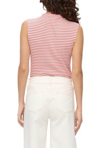 Röd och vitrandig ärmlös topp med rund halsringning, kombinerad med högmidjade vita vida jeans med bakfickor.