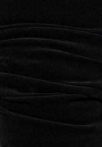 Tessuto di velluto a coste nero con texture a righe verticali, caratterizzato da morbide pieghe che creano un effetto drappeggiato, evidenziando la profondità e la ricchezza del materiale.