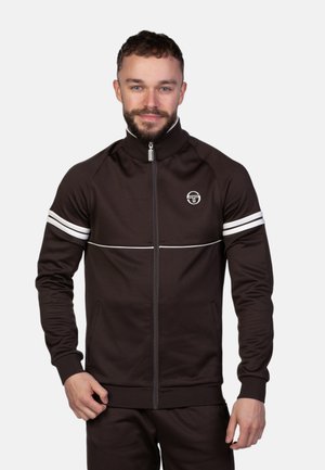 Braune Zip-Jacke mit hohem Kragen, weißen horizontalen Streifen an den Ärmeln und einem runden Logo auf der Brust. Glattes Material, taillierter Schnitt.