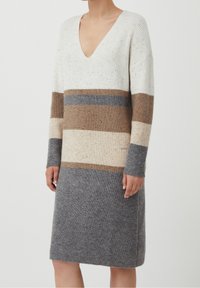 Sukienka dzianinowa z głębokim dekoltem w serek, ozdobiona poziomymi paskami w kolorach kremowym, brązowym, szarym i jasnobeżowym. Faktura prążkowana, z długimi rękawami.