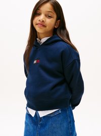 Felpa blu navy con un piccolo logo ricamato. Materiale morbido in misto cotone con vestibilità comoda e polsini a coste. Abbinata a una gonna di jeans.