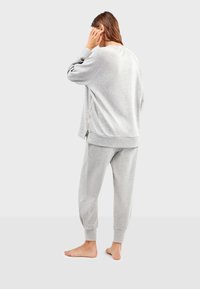 Grijze sweatshirt en bijpassende joggerbroek gemaakt van zacht, gestructureerd materiaal. De sweatshirt heeft ritsdetails en een ontspannen silhouet.