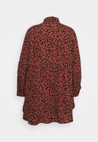 Rostfarbene Kleid mit schwarzen Punkten, langen Ärmeln und leicht geraffter Taille, mit einem kleinen Kragen und glatter Textur.