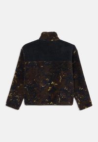 Fleece pulóver v tmavohnedej, žltej a čiernej farbe s vysokým golierom, ktorý má textúrovaný vzor a farebný blokovaný vzor na pleciach.
