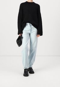 Musta, pörröinen neule pitkähihaisilla hihoilla; vaaleansiniset, korkeat farkut; musta, jämäkkä käsilaukku; massiiviset, mustat kengät.