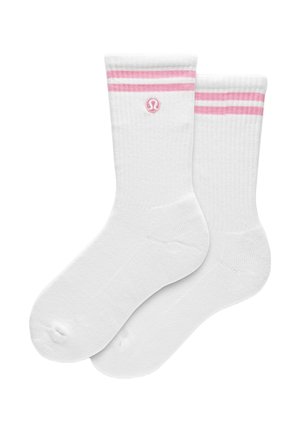 Hvide ankelstrømper med to rosa striber og en rosa cirkulær logo nær toppen, vist side om side.