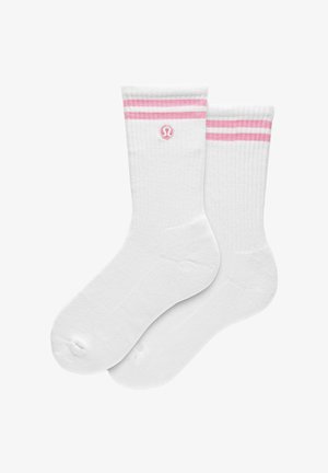 Białe skarpetki typu crew z różowymi podwójnymi paskami i różowym okrągłym logo u góry, pokazane obok siebie.