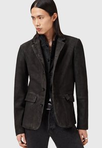 Blazer de cuero negro con un diseño estructurado, solapas de muesca, dos bolsillos frontales y cierre de botón, con una textura ligeramente rugosa.