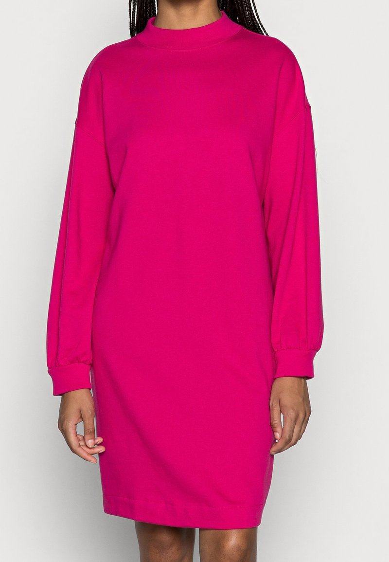 Robe fuchsia à manches longues avec une coupe décontractée, un col montant et des poignets froncés ; fabriquée dans un tissu lisse et léger.