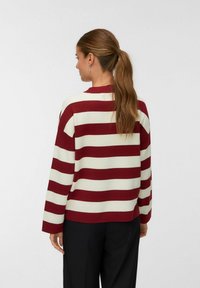 Pull rayé rouge et blanc avec un col rond et des manches longues, doté d'un col en côte et d'une coupe ample.