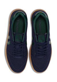 Marinblå sneakers med gröna accenter, övre i mocka, gummisula, perforerad detalj, och platta snören. Varumärkeslogotyp på tungan och sidorna.