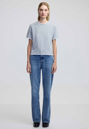 Grijze t-shirt met korte mouwen en witte afwerking, gecombineerd met lichtblauwe jeans. Beide kledingstukken hebben een relaxte pasvorm en een casual ontwerp.