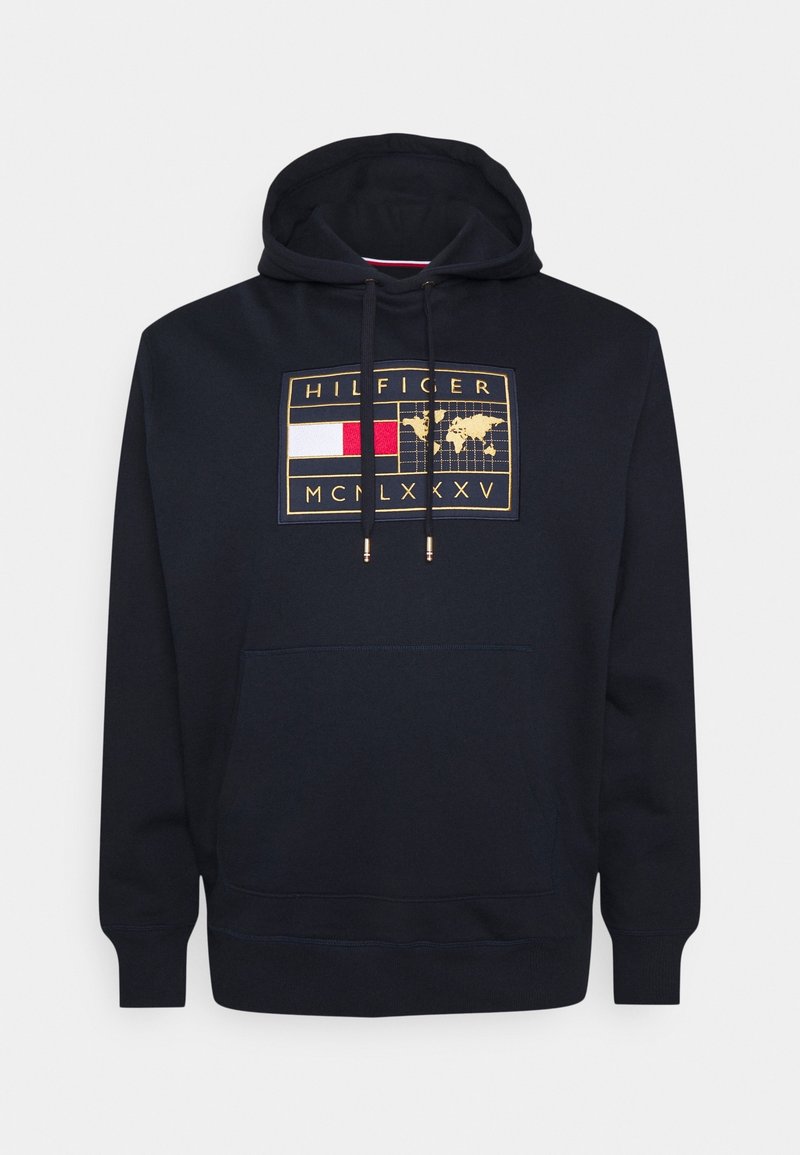 Mörkblå huvtröja med en frontgrafik i guld och flera färger, som visar en världskarta, logotekst och dragskoaccenter. Mjukt tyg, avslappnad passform.