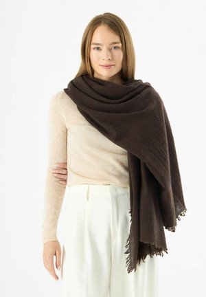 Sciarpa marrone scuro realizzata in tessuto morbido, drappeggiata in modo elegante. Presenta estremità frangiate e una consistenza liscia, indossata sopra un maglione chiaro.