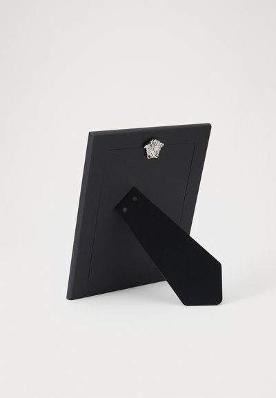 Rama foto neagră cu suprafață lucioasă, având un accent cu un leu argintiu în partea de sus și un suport triunghiular în spate pentru sprijin.