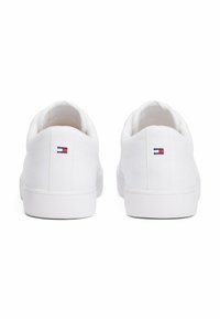 Sneaker bianche in tela con suola piatta e collo imbottito. Presentano un piccolo logo multicolore sul tallone e una dettagliata cucitura testurizzata.