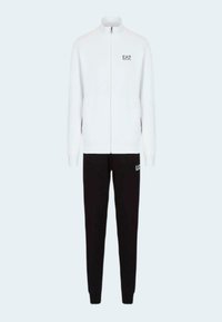 Chaqueta blanca con cremallera y cuello alto, con el logo de EA7, combinada con pantalones negros que también presentan el logo de EA7. Ambos están hechos de un material suave y texturizado.