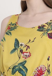 Gelbes Blumenkleid mit grünen Blättern und roten, pinken und weißen Blumen; Rundhalsausschnitt mit gerafftem Taillendetail.