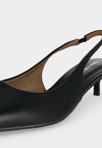 Μαύρη δερμάτινη γόβα slingback με τακούνι kitten, μυτερή μύτη και ταμπά εσωτερική επένδυση σε απλό ανοιχτό φόντο.