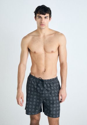 Svarta badshorts med ett upprepande mönster av vita hjärtan, med justerbar dragsko i midjan och lättviktig tyg.