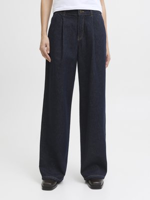Pantaloni in denim blu scuro a gamba larga con due pizzichi frontali, dettagli cuciti e chiusura con cerniera. Texture liscia e vestibilità classica.