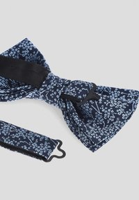 Granatowy krawat w kształcie muszki z kwiatowym wzorem, wykonany z materiału, charakteryzuje się gładką teksturą oraz regulowanym paskiem z plastikowym zapięciem.