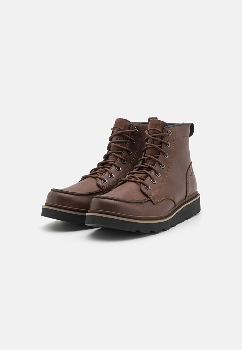 Bottes en cuir marron à lacets avec une tige haute, bout rond, surface texturée et semelle en caoutchouc noir. Caractéristiques : œillets en métal et détails de couture.