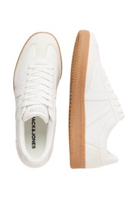 White leather sneakers with a textured gum sole, featuring a classic lace-up design and subtle stitching details on the sides.